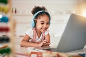 Laptop, home education and happy child elearning, kindergarten homework or remote school work. Knowledge website, learning software and young kid streaming youth development lesson on headphones.